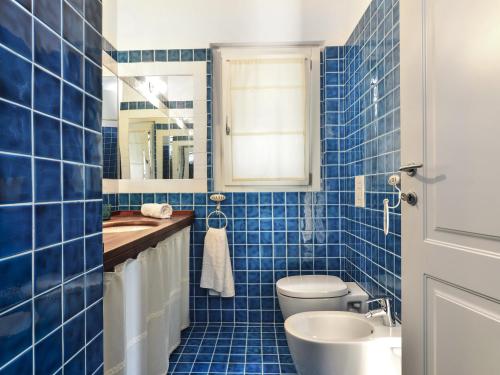 Baño de azulejos azules con aseo y lavamanos en Case Li Conchi F, en Castiadas