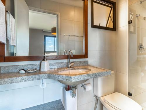 a bathroom with a sink and a toilet and a mirror at VG SUN Apartamento com vista para o mar - High speed internet in Caucaia