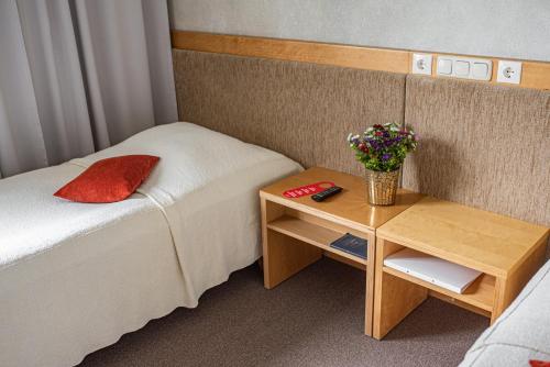 a small room with a bed and a table with flowers at Hotel Sanvilla in Sigulda