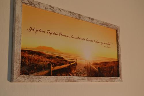 a picture frame hanging on a wall with a picture of a beach at Ferienhaus am Wasser (Knockster Tief) in Hinte