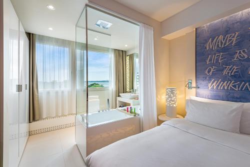 a bedroom with a bed and a bathroom with a tub at N’vY Manotel in Geneva