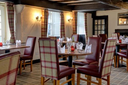 un comedor con mesas, sillas y ventanas en The Winnock Hotel, en Drymen