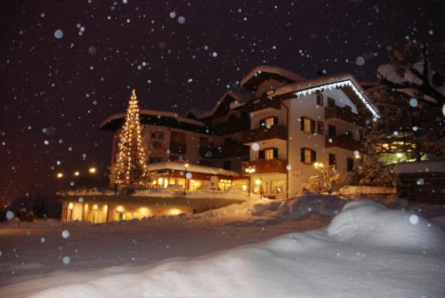 a building with a christmas tree in the snow at La Montanina Hotel in Val di Non in Malosco