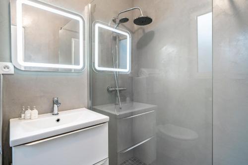 une salle de bain blanche avec un lavabo et une douche dans l'établissement Appartement situé à 1 min de La Croisette, à Cannes