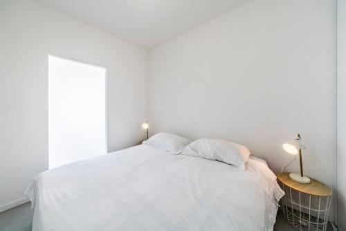 une chambre avec un lit avec des draps blancs et une fenêtre dans l'établissement Appartement situé à 1 min de La Croisette, à Cannes