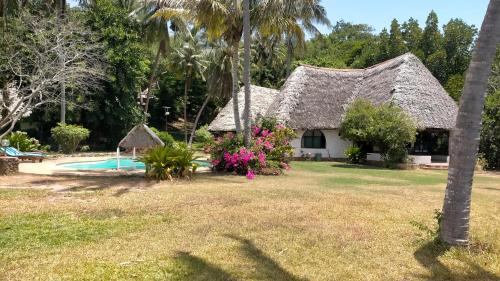 a house with a thatched roof and a swimming pool at Mtwapa Mj Villa Marina in Mombasa