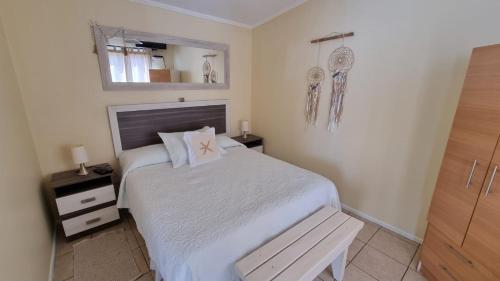 1 dormitorio con cama y banco. en Cabañas Pinamar en La Serena
