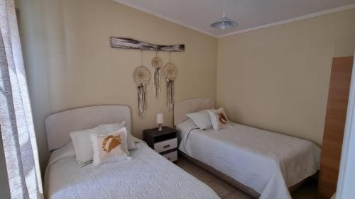 two beds in a room with white walls at Cabañas Pinamar in La Serena