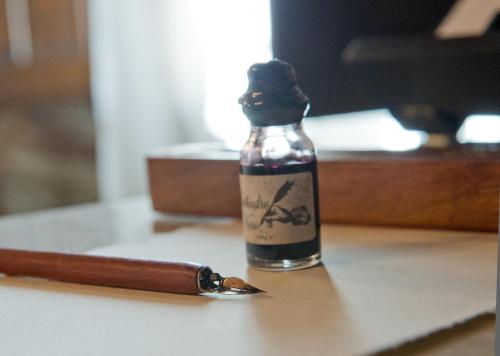 a bottle of alcohol sitting on a table next to a pen at La Casa dels Poetes in Santa Pau