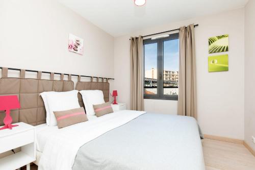 une chambre blanche avec un grand lit et une fenêtre dans l'établissement 3 bedrooms: 200m from Croisette, à Cannes