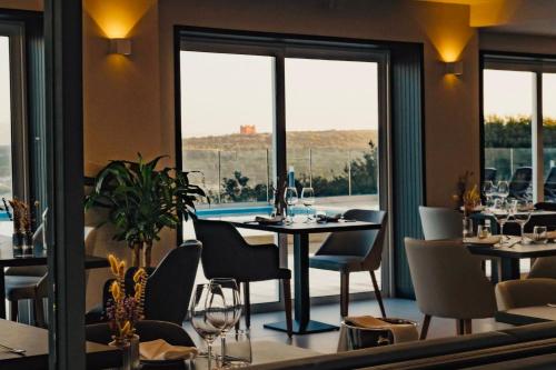 a restaurant with tables and chairs and a large window at Hotel VIU57 in Mellieħa