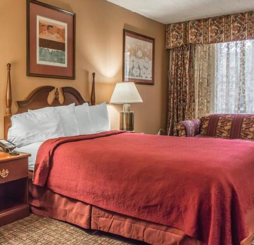 1 dormitorio con cama roja y ventana en FairBridge Inn & Suites Poconos, en Stroudsburg