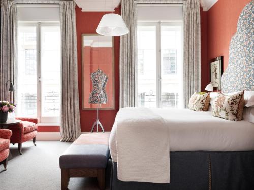 a bedroom with a bed and a chair and windows at Haymarket Hotel, Firmdale Hotels in London