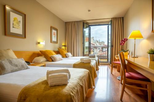 a hotel room with two beds and a desk at Victoria 4 Puerta del Sol in Madrid