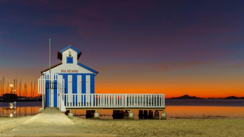 a light house on the beach with the sunset in the background at Hotel Cristina in Los Alcázares