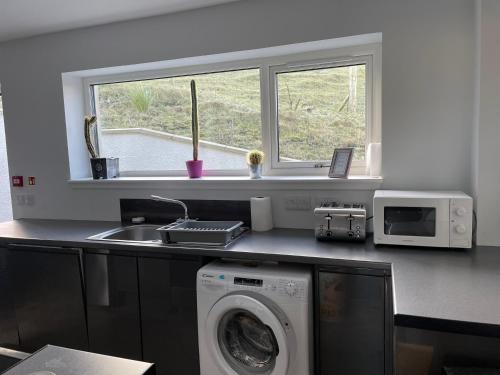 a kitchen with a washing machine and a window at The Bridge Self Catering in Kilmaluag
