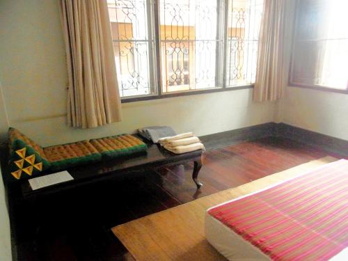 a room with a bench in a room with windows at 28 Rachabutr Hostel in Ubon Ratchathani