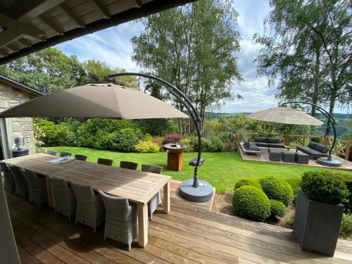 eine Holzterrasse mit Tisch und Sonnenschirm in der Unterkunft Côté Malmedy in Malmedy