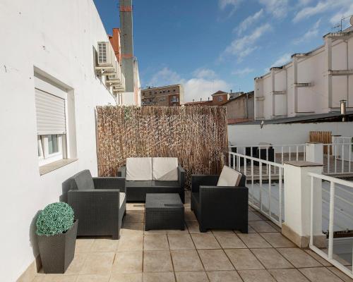 a patio with two chairs and a couch on a balcony at Apartamentos Gladiador in Mérida