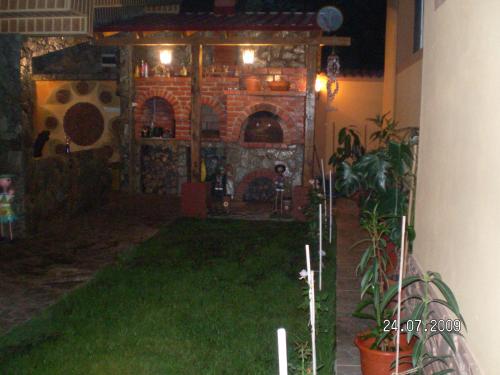a backyard with a brick fireplace and green grass at Motel Davios in Târgu Jiu