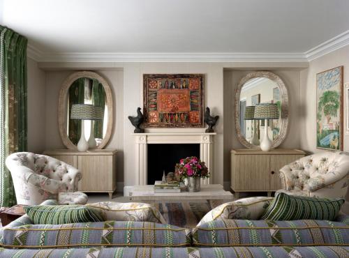 a living room with two chairs and a fireplace at Haymarket Hotel, Firmdale Hotels in London