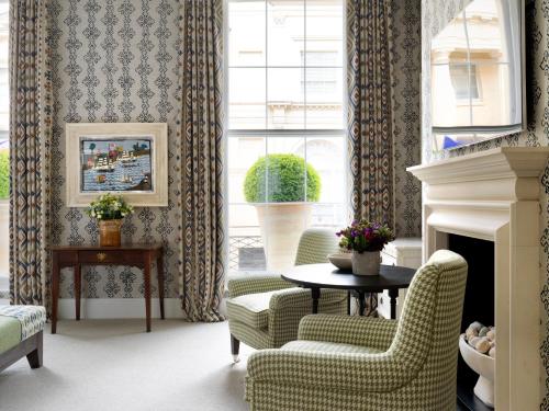 a living room with two chairs and a table and a fireplace at Haymarket Hotel, Firmdale Hotels in London