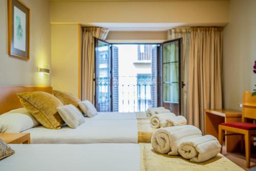 a hotel room with two beds and a balcony at Victoria 4 Puerta del Sol in Madrid