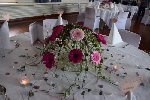 a table with a centerpiece of pink flowers and candles at Hotel Hecht in Rheineck