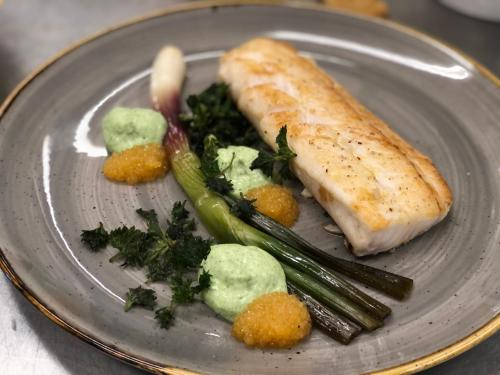 a plate of food with a piece of fish and vegetables at Bommersvik Hotell & Konferens in Järna