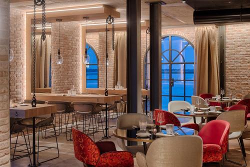 a restaurant with tables and chairs and windows at NH Collection Murano Villa in Murano