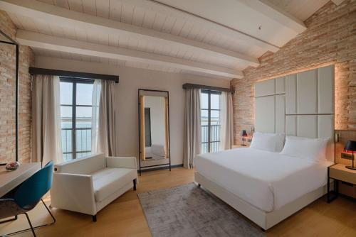 - une chambre avec un lit blanc et une chaise blanche dans l'établissement NH Collection Murano Villa, à Murano