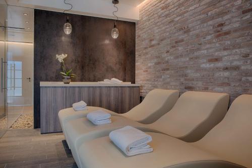 a salon with white chairs and a brick wall at NH Collection Murano Villa in Murano