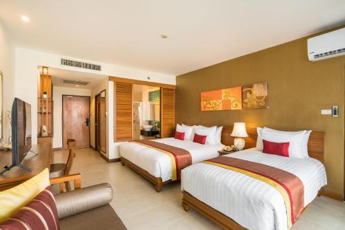 a hotel room with two beds and a television at Cosy Beach Hotel - SHA Extra Plus in Pattaya South