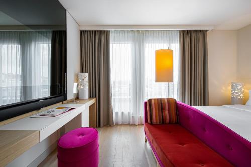 a hotel room with a large bed and a red couch at N’vY Manotel in Geneva