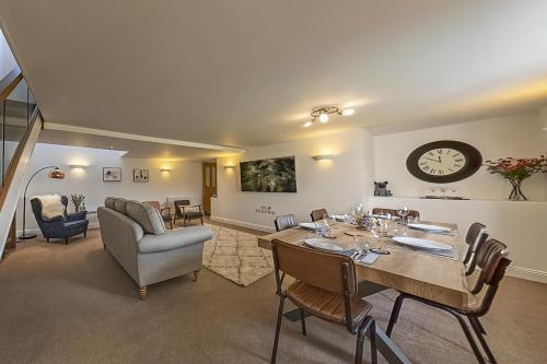 sala de estar con mesa, sillas y reloj en 3 Bedroom Barn Conversion -Garden View - Ty Cerrig Barn en Corwen