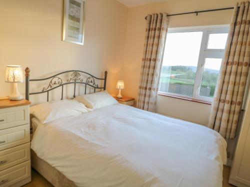 a bedroom with a white bed and a window at Derryallen View in Enniskillen