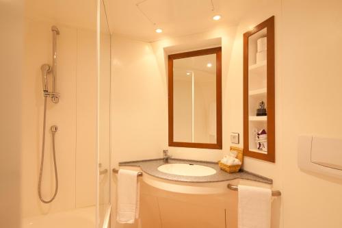 a bathroom with a sink and a shower with a mirror at Villa Mariale by Popinns in Lourdes