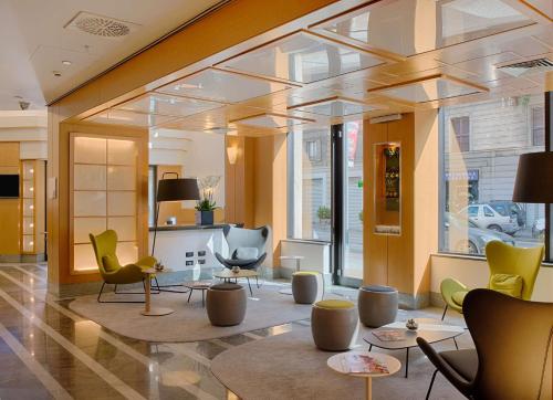 un vestíbulo con sillas y mesas en un edificio en NH Milano Machiavelli, en Milán