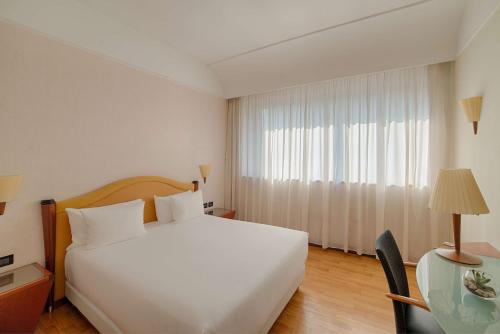 um quarto com uma grande cama branca e uma janela em NH Milano Machiavelli em Milão