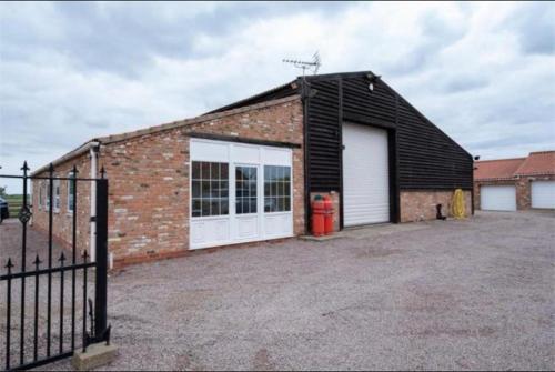 a brick building with two garage doors and a fence at 2 bedroom Orchard View Cottage Pet Friendly Free onsite parking and WiFi near pilgrim hospital, Boston in Boston