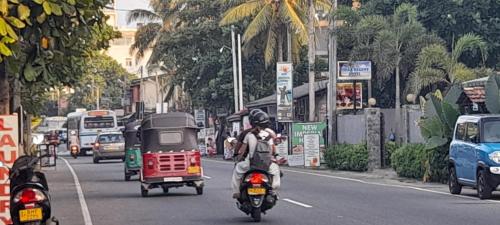 a man riding a motorcycle down a busy city street at New Imperial Hotel in Hikkaduwa