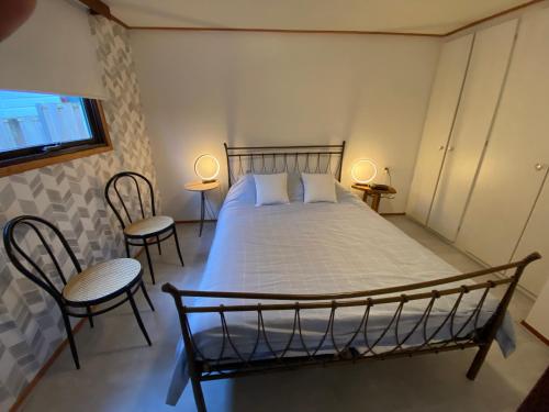 a bedroom with a bed with two chairs and two lamps at Vakantiehuisje Makkum NL - T11 in Makkum