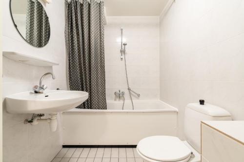 a bathroom with a sink and a toilet and a bath tub at Lange Duinen in Hollum