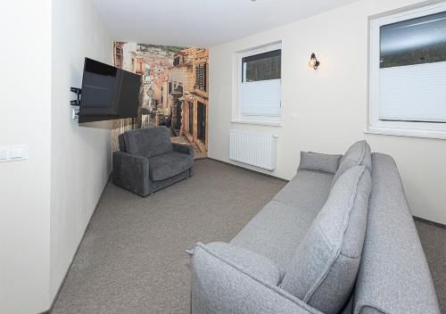 a living room with a gray couch and a television at Apartament Piano in Świeradów-Zdrój