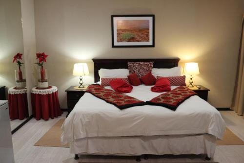 a bedroom with a bed with red pillows on it at Amjicaja Guesthouse, Tours & Rentals in Walvis Bay