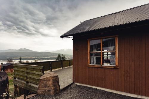 a wooden cabin with a deck and a window at Björkin – Cozy Cabin with excellent view in Akureyri