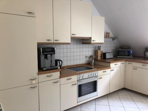 eine Küche mit weißen Schränken und einem Herd mit Backofen in der Unterkunft Charmante 2-Zimmer Wohnung in Hoisdorf