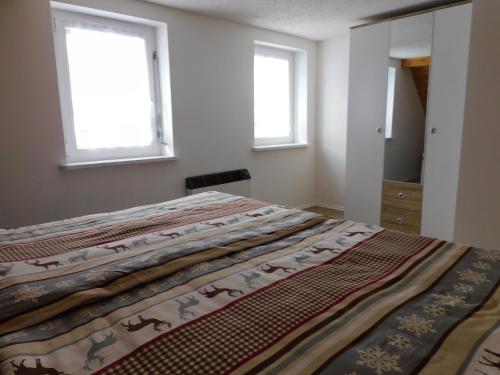 a bed in a bedroom with two windows at Haus Eugen in Presseck