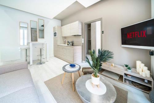 uma sala de estar com um sofá e uma televisão em Frontière Monaco, appartement moderne rénové - AH em Beausoleil