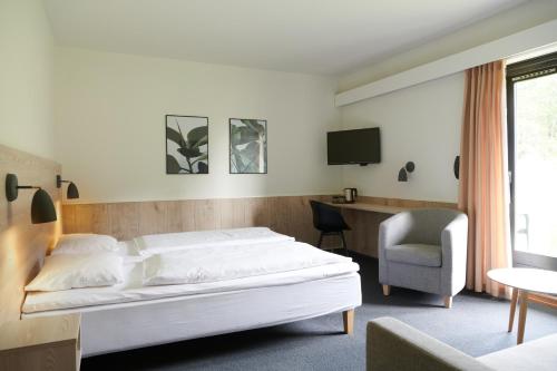 Montra Hotel Hanstholm في هانستهولم: غرفة نوم بسرير ومكتب وكرسي